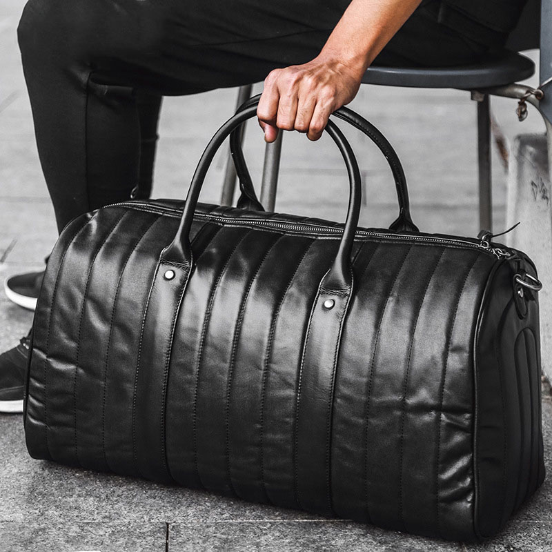 Regal Black Leather Duffel Bag on floor while a man's hand is holding it s